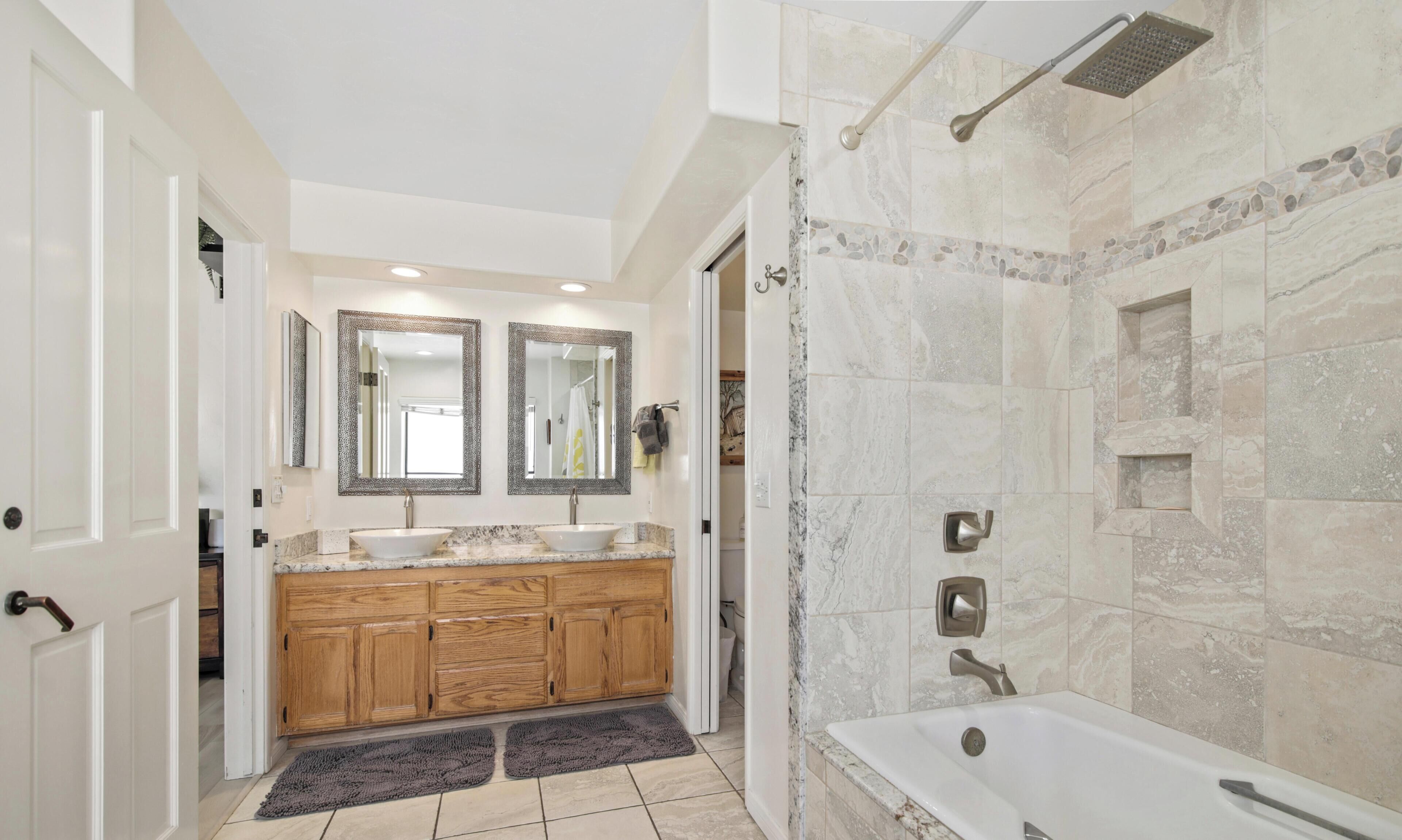 Une salle de bain moderne avec une baignoire îlot, un meuble-lavabo double avec miroirs et un espace douche doté d’une douchette à pluie.