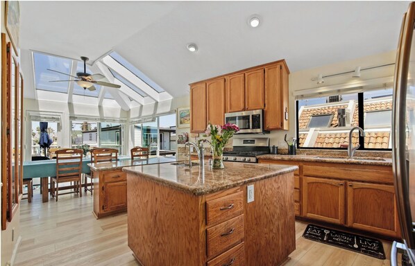 A spacious kitchen with wooden cabinets, a central island, and a large window providing natural light.