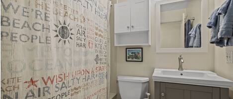 A bathroom with a white toilet, a sink with a mirror above it, and a towel rack with towels.