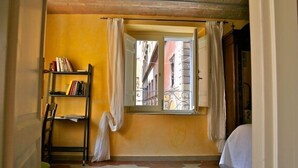 Une pièce avec une fenêtre, une bibliothèque et une chaise.