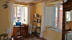 Une pièce comprenant un bureau, une chaise et une fenêtre avec des rideaux.