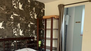 Un dormitorio con una cama grande, cabecera de madera, pared con estampado de camuflaje y baño visible a través de una puerta abierta.