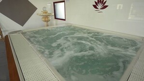Un jacuzzi con el logotipo de loto en la pared, un cuadro enmarcado y una fuente decorativa.