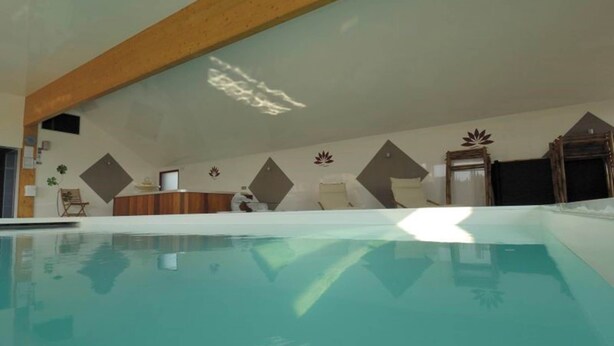 Una piscina interior con viga de techo de madera, una recepción y diseños decorativos en la pared.
