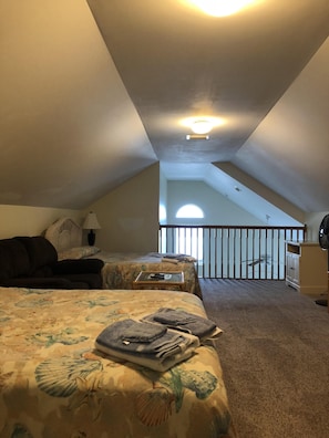 Two beds with floral-patterned bedding are situated in this room, which features a balcony with a railing offering a view of the outdoors.