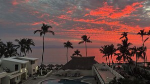 A resort with a pool, lounge chairs, and palm trees against a sunset sky. - Experience the Best of Bucerias Beach Front Living (Bucerias)