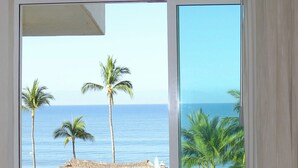 Una habitación con vista al océano, una mesa con sillas y una pared verde.