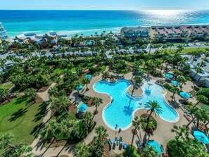 An aerial view of a resort with a large, uniquely shaped pool surrounded by palm trees and lounge areas. -  Designer decor, Direct View, Very clean and well maintaned. Sleeps 6.  (Destin)