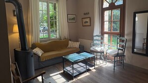 A cozy room with a sofa, a table, a chair, a fireplace, and large windows. - 3 of cottage oak: Nestled in a clearing in the middle of Vexin regional park (Chambly)