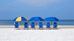 Une plage avec des parasols bleus et jaunes et des chaises longues assorties.