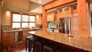 A modern kitchen with wooden cabinets, stainless steel appliances, and a granite countertop. - Exceptional Ski-in/Walk-out Home - 4100 Sft (Golden)