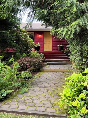 A house with a red door, a brick exterior, and a stone pathway leading to the entrance.