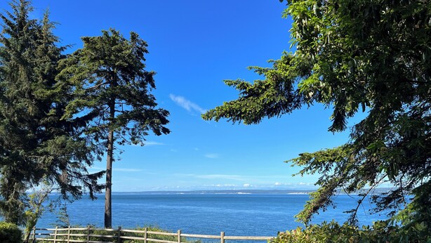 A view of a wooden deck with two Adirondack chairs facing a body of water, surrounded by trees and a wooden fence. - Top-Rated Waterfront Retreat Near Port Townsend (Nordland)
