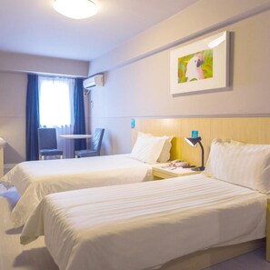 A hotel room with two beds, a desk, a chair, an air conditioning unit, and a painting on the wall.