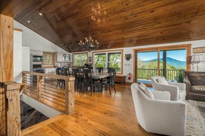 A spacious kitchen with wooden ceiling, a dining area with a round table, and a living room with a sofa and a view of the mountains. - Luxury Mountain Cabin w/ Hot Tub, Game Room & Views (Boone)