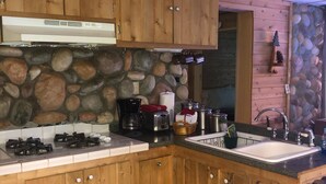Une cuisine avec des meubles en bois, un mur en pierre et un évier.