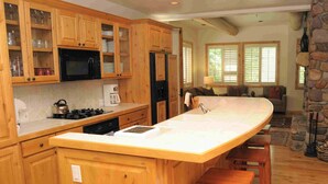 A kitchen with wooden cabinets, a large island, and a stone accent wall.