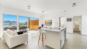 A modern kitchen with a central island, large windows with a view, and a white dining area. - Oceanfront amazing 2 BR Villa - 2 min from the beach (Beacon Hill)