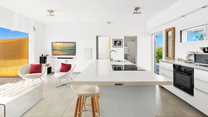 A modern kitchen with a large island, white cabinetry, and a view of the outdoors. - Oceanfront amazing 2 BR Villa - 2 min from the beach (Beacon Hill)