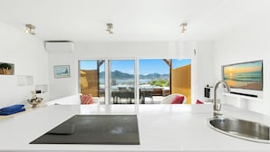 A modern kitchen with a large island, a dining area with a view, and a sliding glass door leading to a balcony. - Oceanfront amazing 2 BR Villa - 2 min from the beach (Beacon Hill)