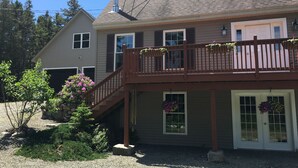 Une maison à deux étages avec un balcon, un garage et un petit jardin.