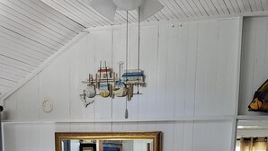 A bedroom with a large bed, a ceiling fan, a mirror, and a bedside table with a lamp.