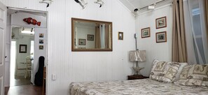 Un dormitorio con cama, espejo, lámpara con forma de estrella de mar y cuadros en la pared.