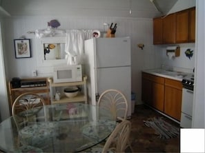 Compact kitchen with a dining area, featuring a refrigerator, microwave, and wooden cabinets.