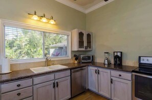 A kitchen with a window, sink, cabinets, a toaster, and a coffee maker. - Aloha Villa: AC, Garden, Short Walk to Poipu Beach (Koloa)
