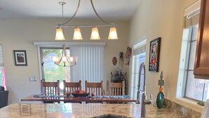 A kitchen with granite countertops, wooden cabinets, a stainless steel dishwasher, and a dining area with a chandelier. - Beautiful Home w/ Pool; Clean, Quiet, Secure - near Mayo Clinic; Hiking/Golfing (Scottsdale)