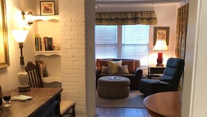 A cozy living room with a fireplace, a dining area with a table and chairs, and a kitchen area with a counter and cabinets. - Bungalow located in downtown Tryon, N.C.  (Tryon)