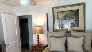 A bedroom with a bed, a bedside lamp, a framed picture on the wall, and a door leading to another room. - Bungalow located in downtown Tryon, N.C.  (Tryon)