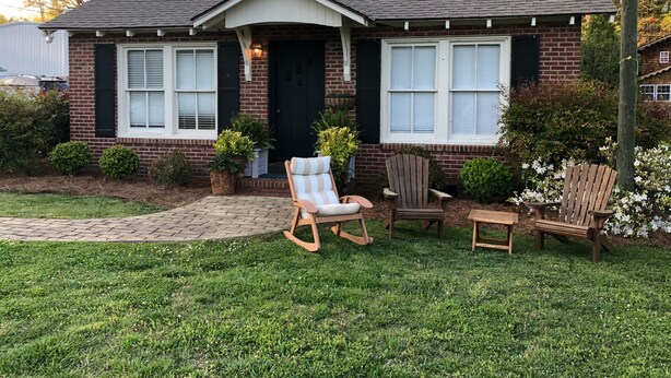 A two-story brick house with a dark roof, white-framed windows, and a front porch with a rocking chair and two wooden chairs. - Bungalow located in downtown Tryon, N.C.  (Tryon)