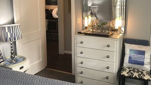 Ein Schlafzimmer mit einem Bett, einem Schminktisch, einem Spiegel, einer Lampe und einem Stuhl.