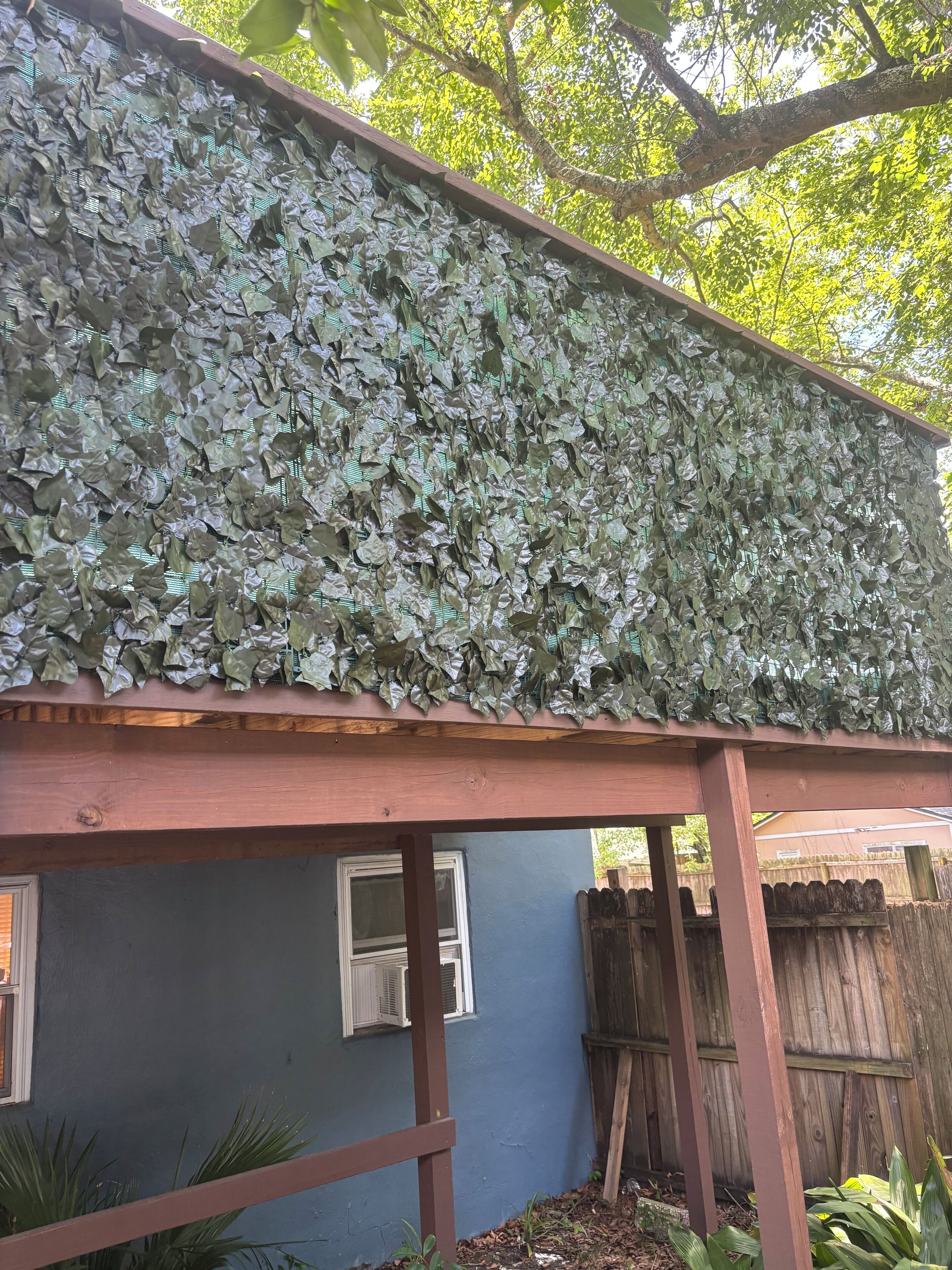Une maison avec un porche en bois et un mur recouvert de verdure.