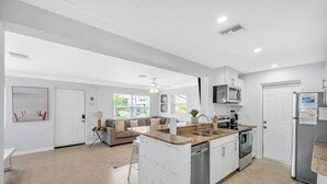 Una cocina moderna con una isla central, electrodomésticos integrados y un comedor con sofá.