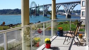 Ein Balkon mit Blick auf eine Brücke über dem Wasser, ein Stoppschild und Kübelpflanzen.