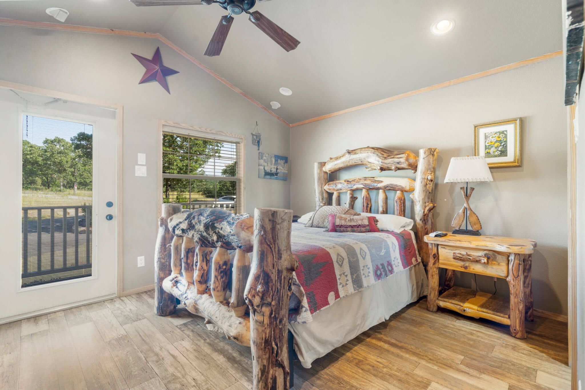 Un dormitorio con cama, mesita de noche, ventilador de techo, decoración de estrellas y ventana.