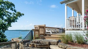 A coastal property with a stone staircase leading to a white porch with outdoor furniture.