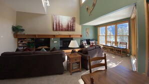 A spacious living room with a fireplace, a large window, and a cozy seating area.