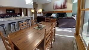 A spacious living area with a wooden dining table, kitchen, and seating area.