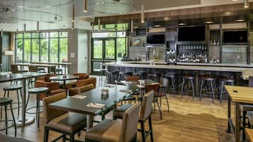 A modern restaurant with a bar area, multiple seating options, and a view of the outdoors.