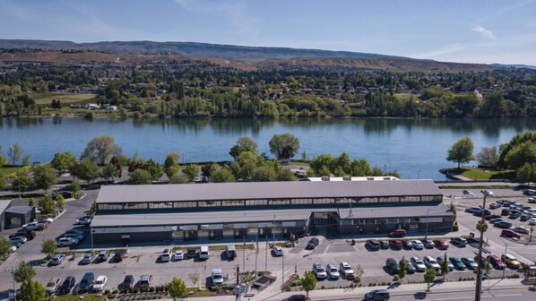 A large building with a parking lot in front, surrounded by trees and a lake. - Hilton Garden Inn Wenatchee (Wenatchee)