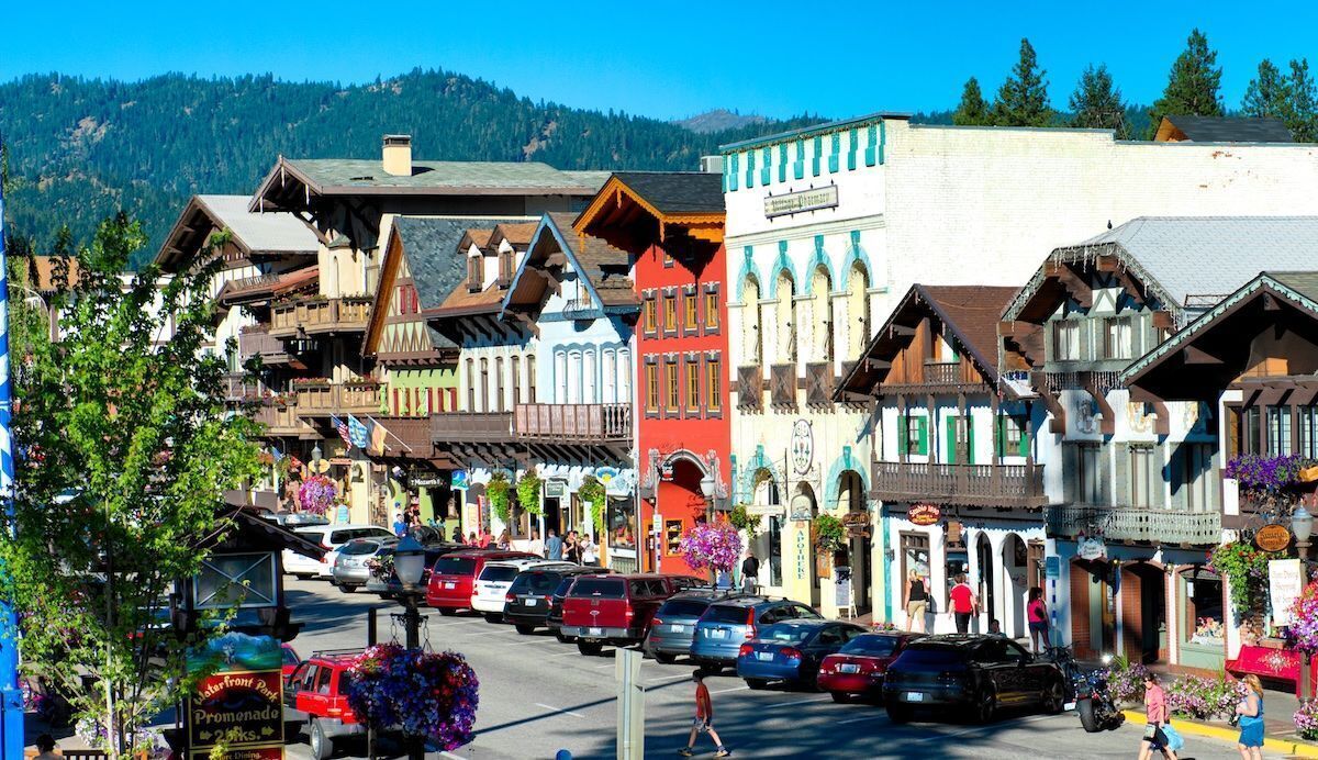 A street lined with colorful buildings, a pedestrian walkway, and parked cars.