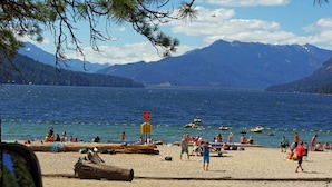 Une plage avec des gens, un poste de surveillance pour les sauveteurs, et des montagnes en arrière-plan.