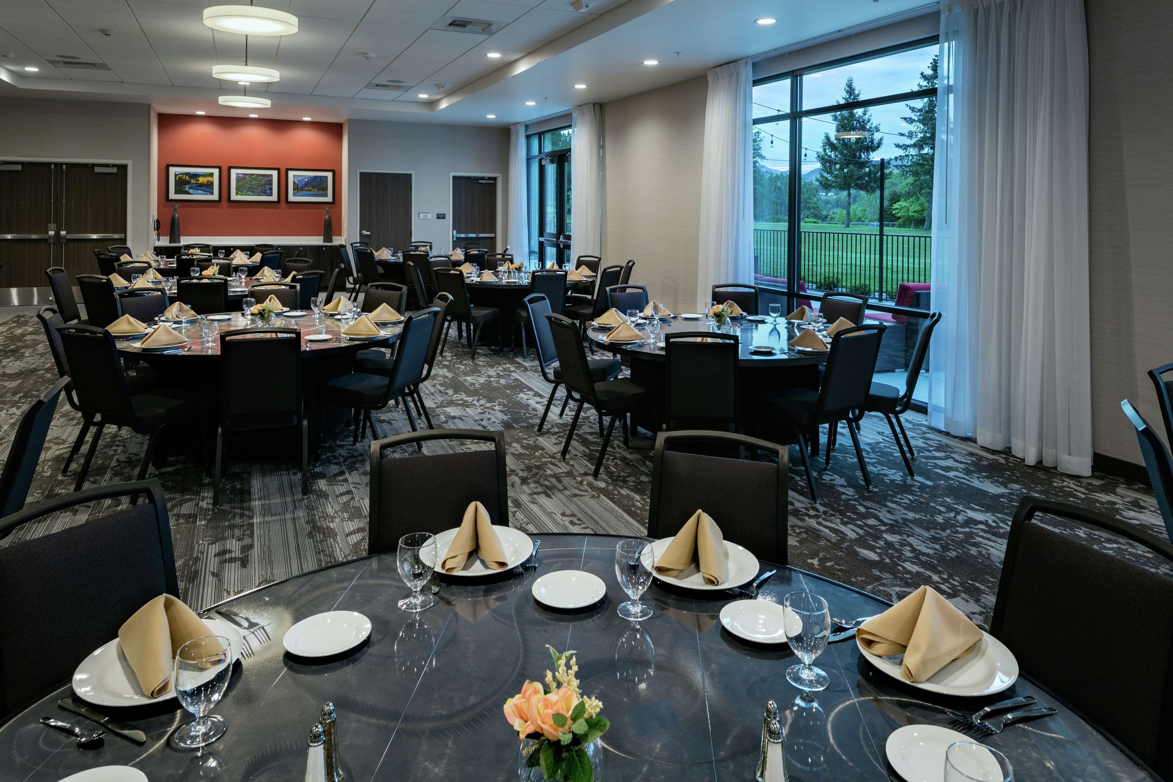 A conference room with round tables, chairs, and a carpeted floor.