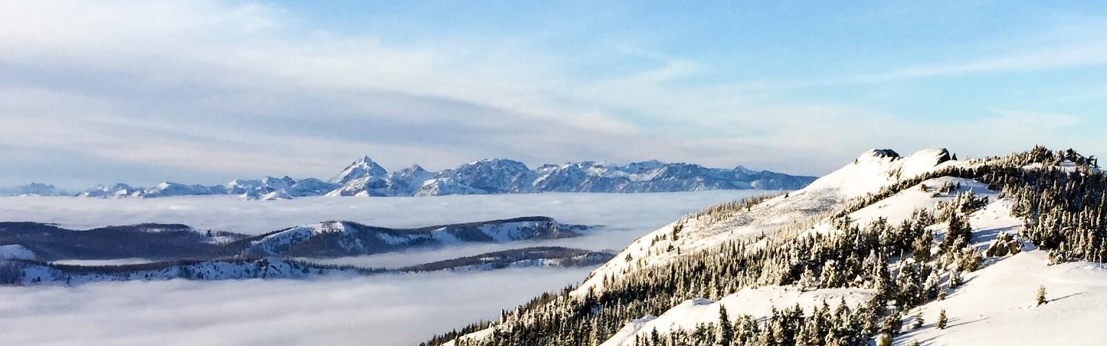 Vista panorâmica de uma paisagem montanhosa coberta de neve com céu claro.