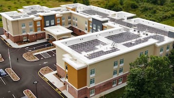 A multi-story building with a rooftop parking area and solar panels.