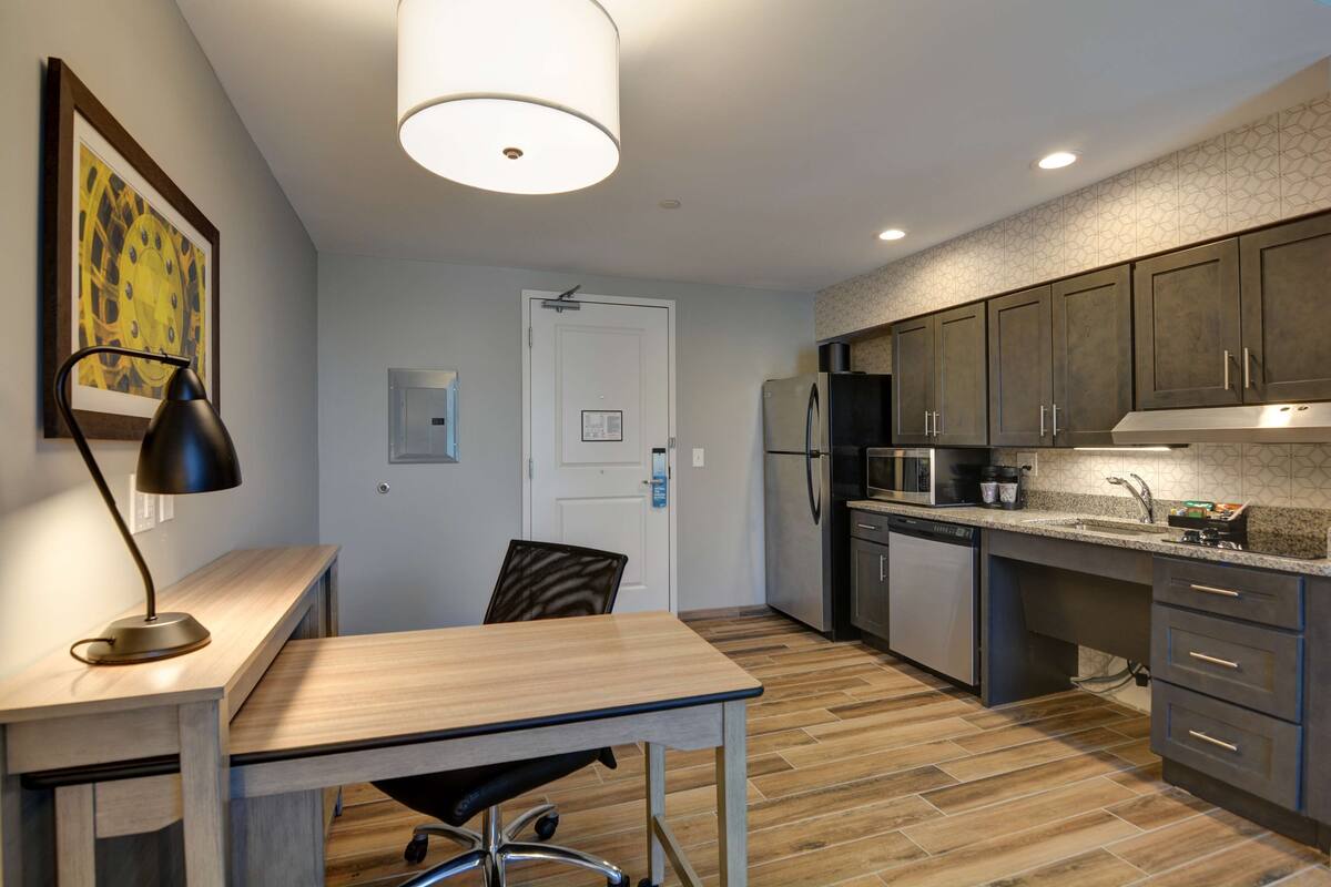 A modern kitchen with a wooden countertop, built-in appliances, and a dining area with a table and chair.