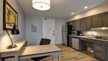Una cocina moderna con encimera de madera, electrodomésticos integrados y una zona de comedor con mesa y silla.